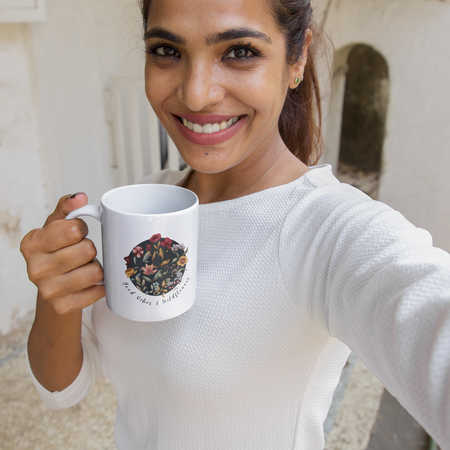 Lifestyle shot of the Good Vibes & Wildflowers Ceramic Mug filled with a warm beverage, highlighting the comfortable C-handle and the perfect size for enjoying a drink.