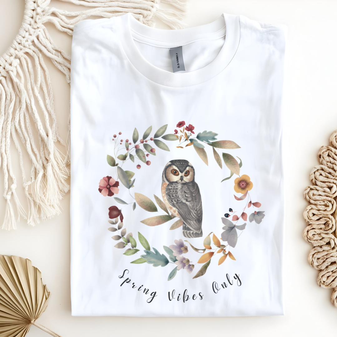 Flat lay of the "Spring Vibes Only" Tee, highlighting the soft, 100% US cotton fabric, classic crew neck, and the adorable owl and floral wreath design. Color White