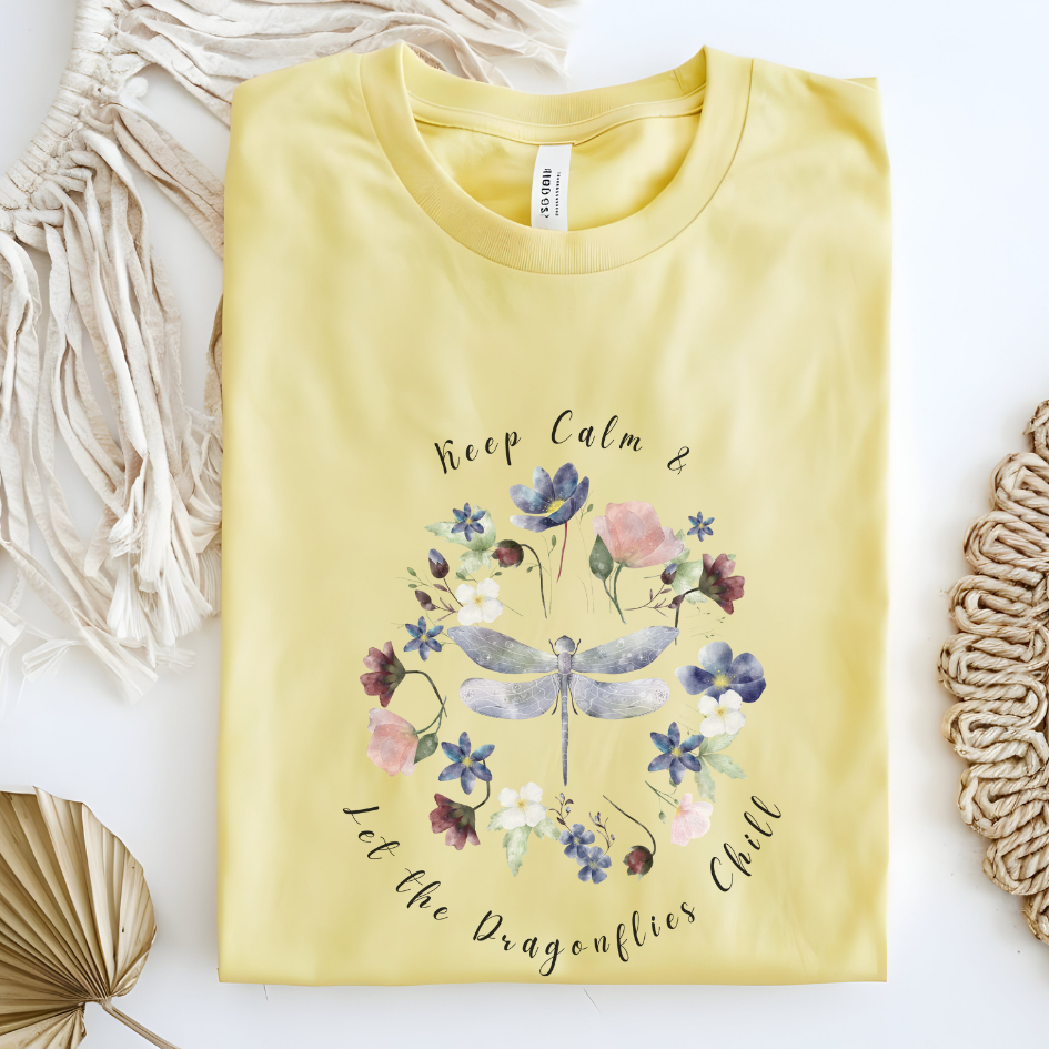 Flat lay of the "Chill Spring! Keep Calm & Let the Dragonflies Chill" T-Shirt, highlighting the soft, 100% ring-spun cotton fabric, classic crew neck, and the adorable dragonfly and floral wreath design. Color Cornsilk