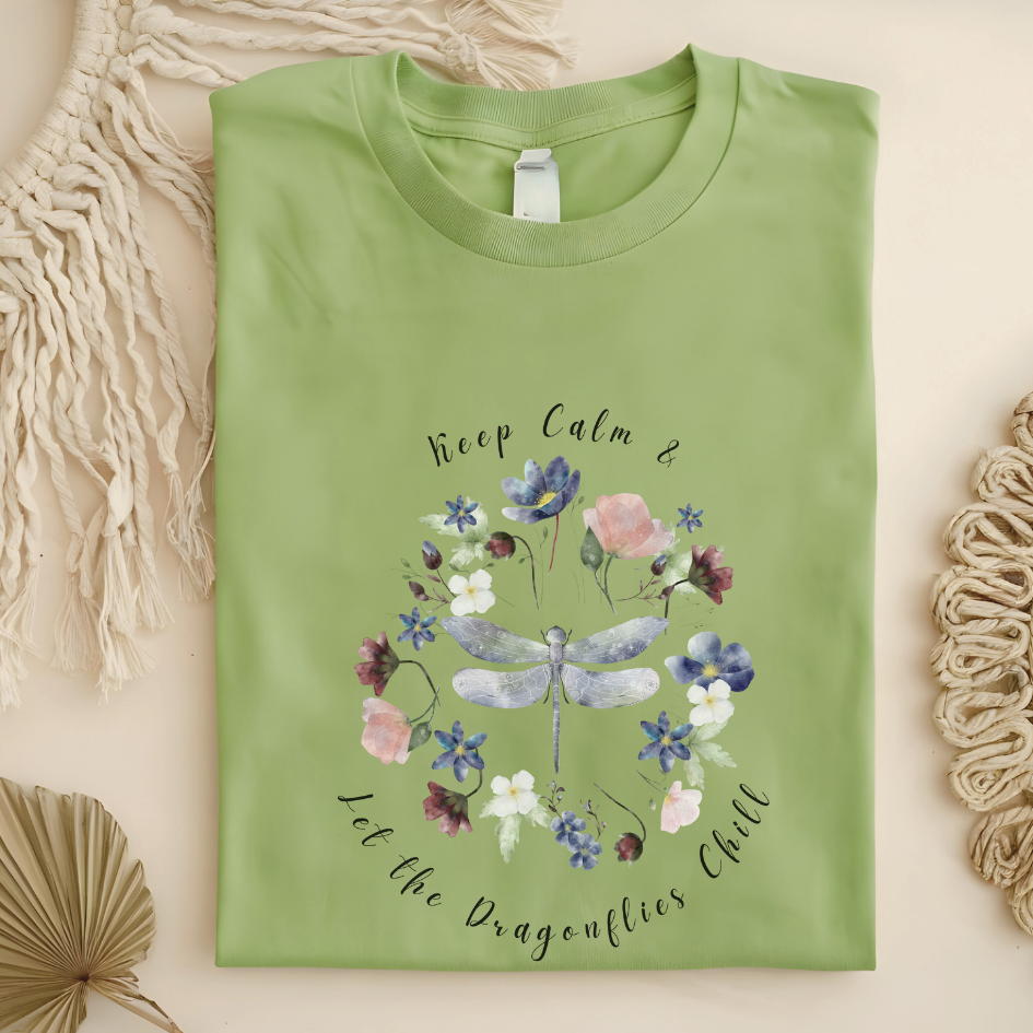 Flat lay of the "Chill Spring! Keep Calm & Let the Dragonflies Chill" T-Shirt, highlighting the soft, 100% ring-spun cotton fabric, classic crew neck, and the adorable dragonfly and floral wreath design. Color Pistachio