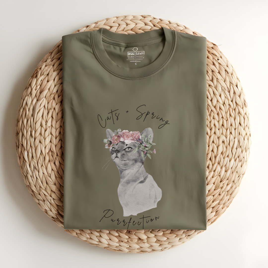 Flat lay of the "Purrfect Spring Vibes" T-Shirt, highlighting the garment-dyed fabric's texture and the durable double-needle stitching. The watercolor cat and floral crown design. Color Khaki