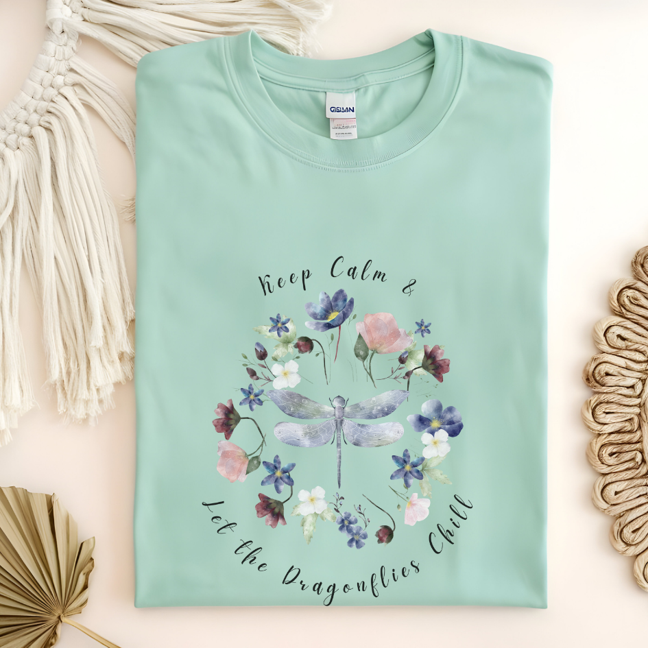 Flat lay of the "Chill Spring! Keep Calm & Let the Dragonflies Chill" T-Shirt, highlighting the soft, 100% ring-spun cotton fabric, classic crew neck, and the adorable dragonfly and floral wreath design. Color Mint green