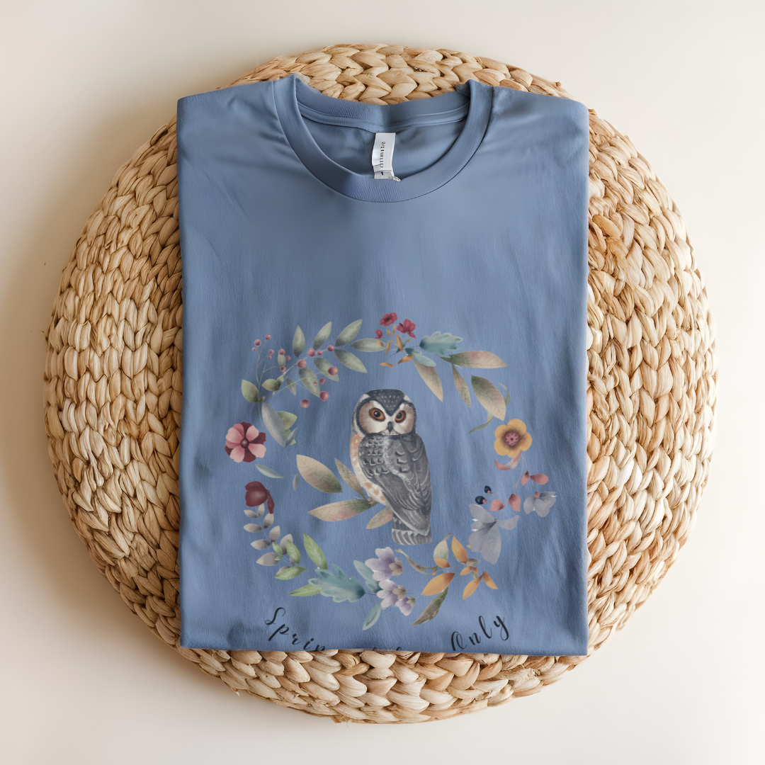 Flat lay of the "Spring Vibes Only" Tee, highlighting the soft, 100% US cotton fabric, classic crew neck, and the adorable owl and floral wreath design. Color Heather Indigo