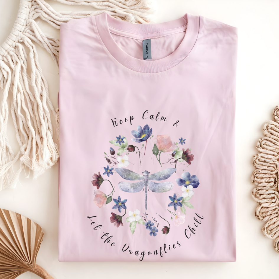 Flat lay of the "Chill Spring! Keep Calm & Let the Dragonflies Chill" T-Shirt, highlighting the soft, 100% ring-spun cotton fabric, classic crew neck, and the adorable dragonfly and floral wreath design. Color Light Pink