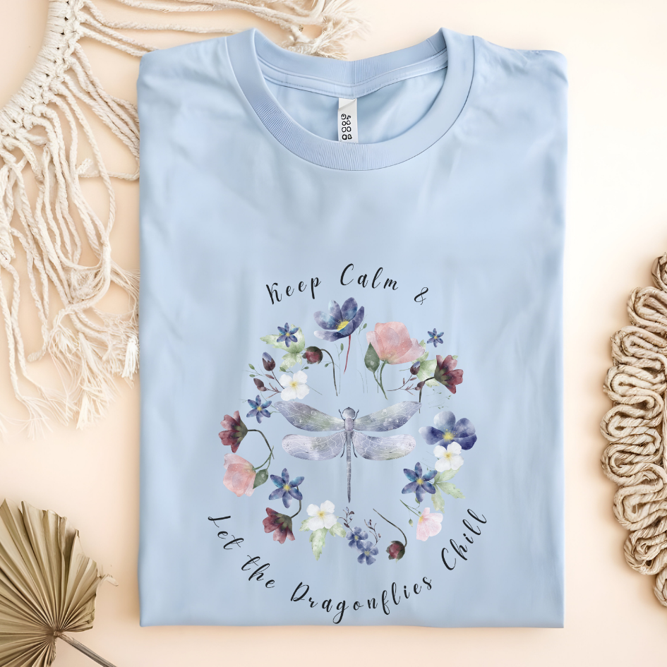 Flat lay of the "Chill Spring! Keep Calm & Let the Dragonflies Chill" T-Shirt, highlighting the soft, 100% ring-spun cotton fabric, classic crew neck, and the adorable dragonfly and floral wreath design. Color Light Blue