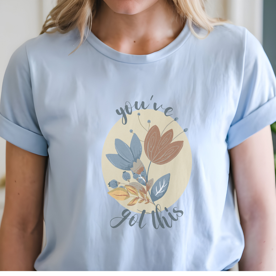 Cotton unisex t-shirt with "you've got this" motivational text and artistic floral design in blue, terracotta, and cream colors. Color light blue