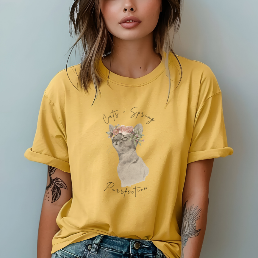 "Purrfect Spring Vibes" Personalized Unisex Garment-Dyed T-Shirt, featuring a charming watercolor illustration of a grey cat wearing a crown of pink roses and green leaves, with the text "Cats + Spring Purrfection" above and below, modeled by a woman wearing size L for an oversized effect. Color Butter