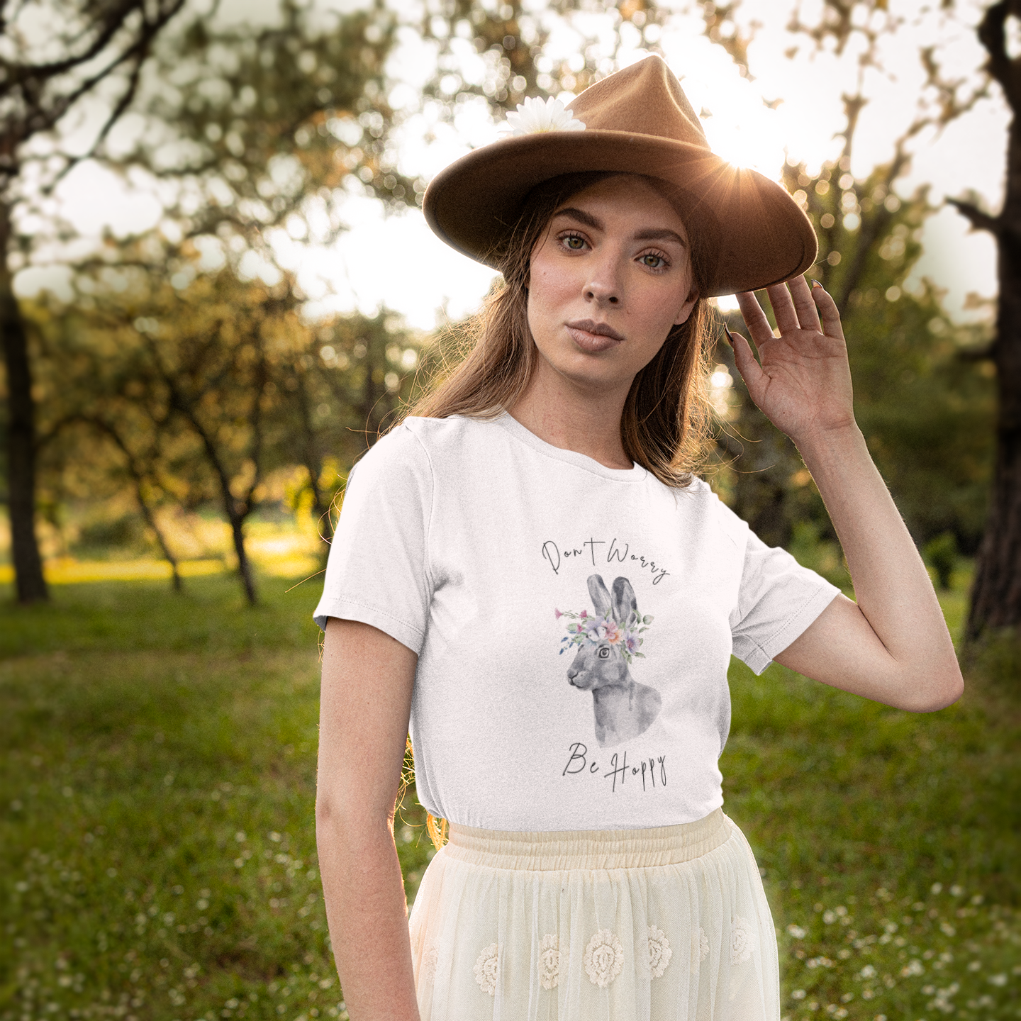 Lifestyle shot of a person wearing the "Hoppin' into Spring" T-Shirt strolling through a blooming park. The charming watercolor rabbit and floral wreath design adds a touch of springtime elegance.