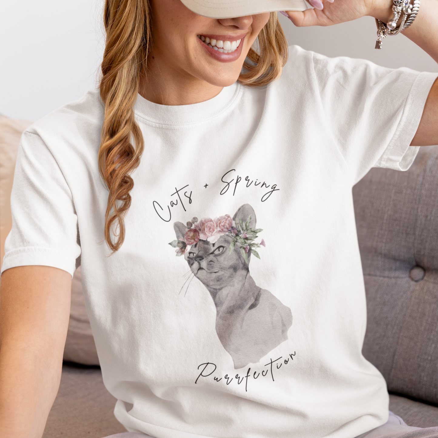 "Purrfect Spring Vibes" Personalized Unisex Garment-Dyed T-Shirt, featuring a charming watercolor illustration of a grey cat wearing a crown of pink roses and green leaves, with the text "Cats + Spring Purrfection" above and below, modeled by a woman wearing size L for oversize effect. Color White