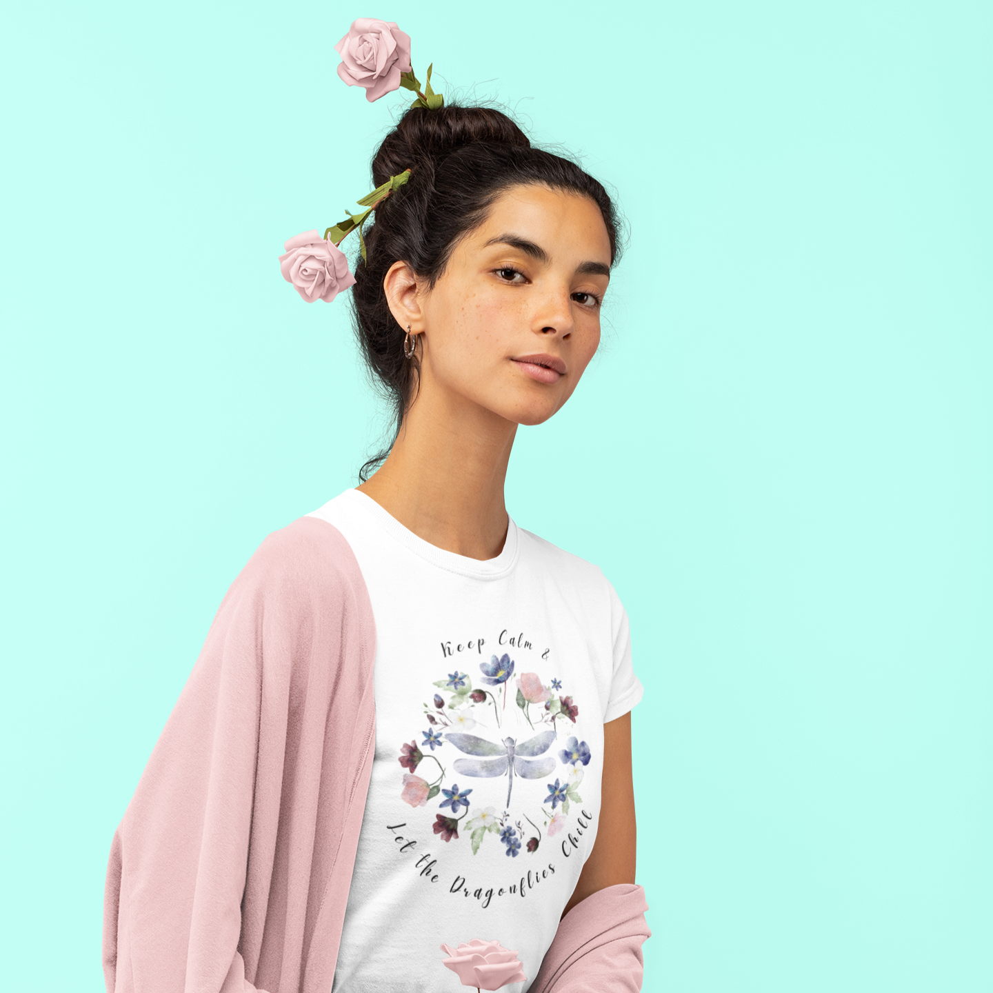 Chill Spring! Keep Calm & Let the Dragonflies Chill" Unisex Soft Style T-Shirt, featuring a charming illustration of a delicate dragonfly at the center of a circular wreath of blooming wildflowers, with the text "Keep Calm & Let the Dragonflies Chill" elegantly encircling the design, modeled by a woman wearing size S. Color White