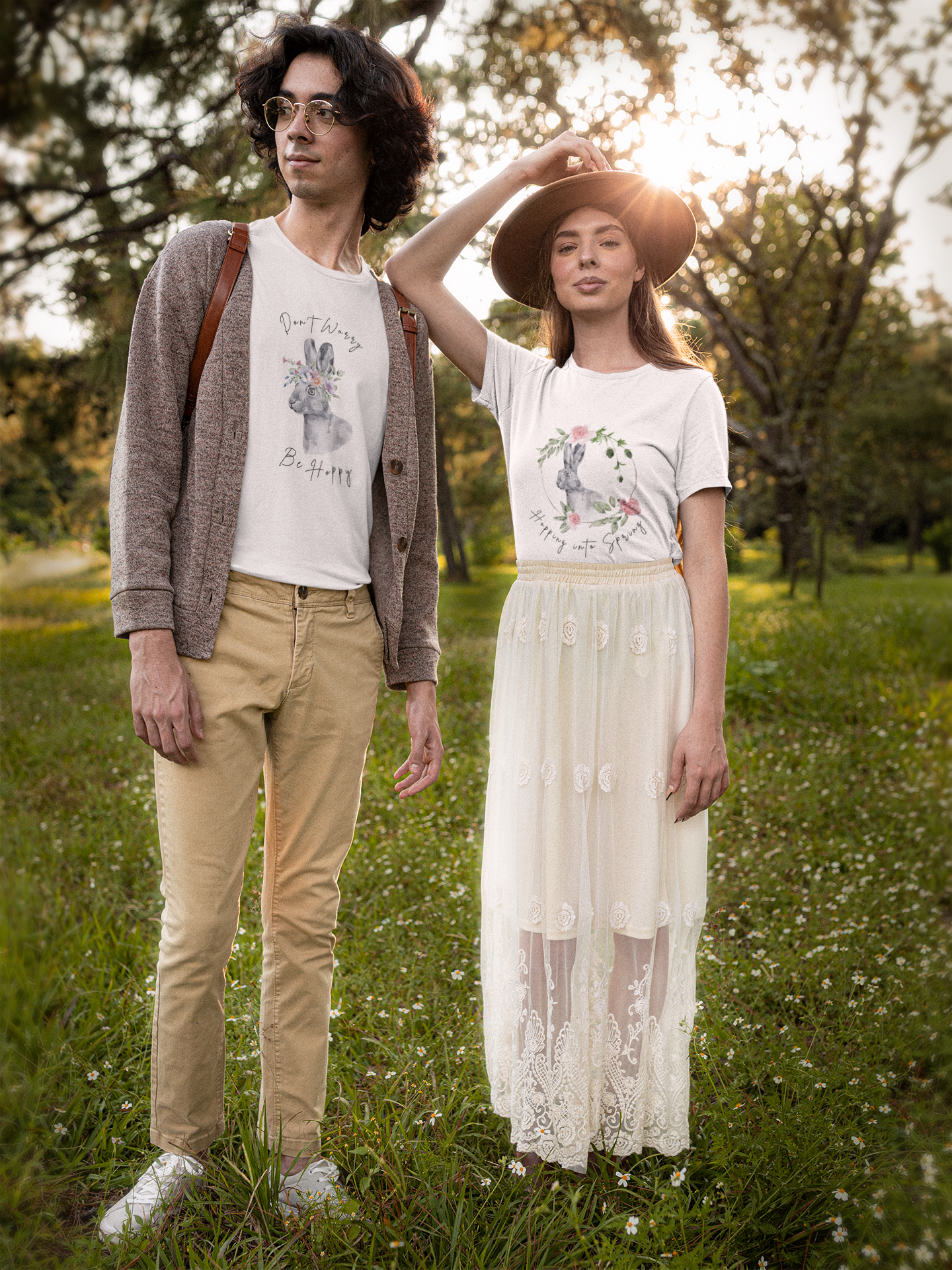 Lifestyle shot of a couple wearing the "Hoppin' into Spring" T-Shirt strolling through a blooming park. The charming watercolor rabbit and floral wreath design adds a touch of springtime elegance.