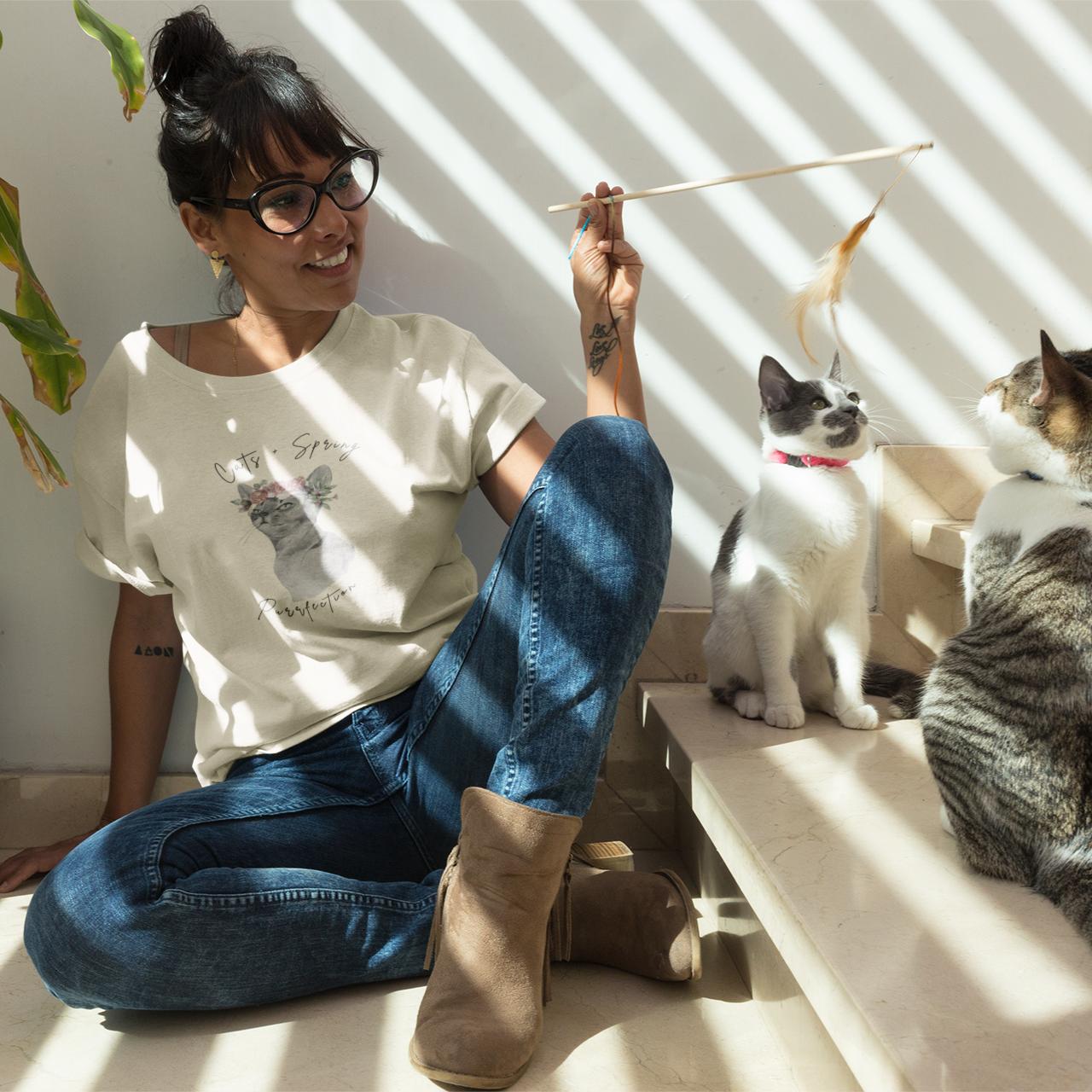 Lifestyle shot of a person wearing the "Purrfect Spring Vibes" Personalized T-Shirt while playing with her cats