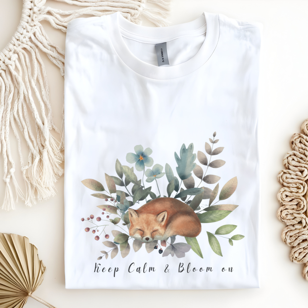 Flat lay of the "Keep Calm & Bloom On" T-Shirt, highlighting the soft, 100% US cotton fabric and classic crew neck. The watercolor fox and floral design are clearly visible. Color White
