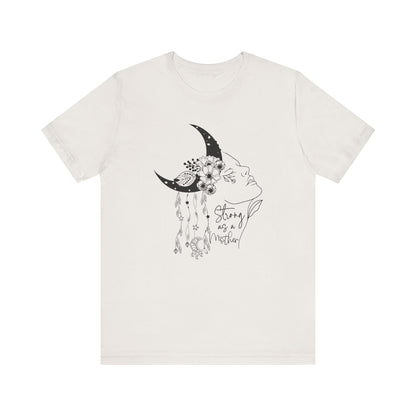 Flat lay of the "Strong as a Mother" T-Shirt, highlighting the soft Airlume cotton fabric and classic crew neckline. Color White Vintage. The graphic is clearly visible, showing the woman's profile, crescent moon, flowers, and charms in detail.
