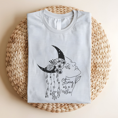 Close-up view of the "Strong as a Mother" graphic, showcasing the intricate details of the crescent moon with its stippled texture, the vibrant flowers nestled within it, and the flowing lines of the woman's profile. The dangling charms add a touch of whimsy. The words "Strong as a Mother" are written in a delicate script, font beneath the graphic. Color  Ash