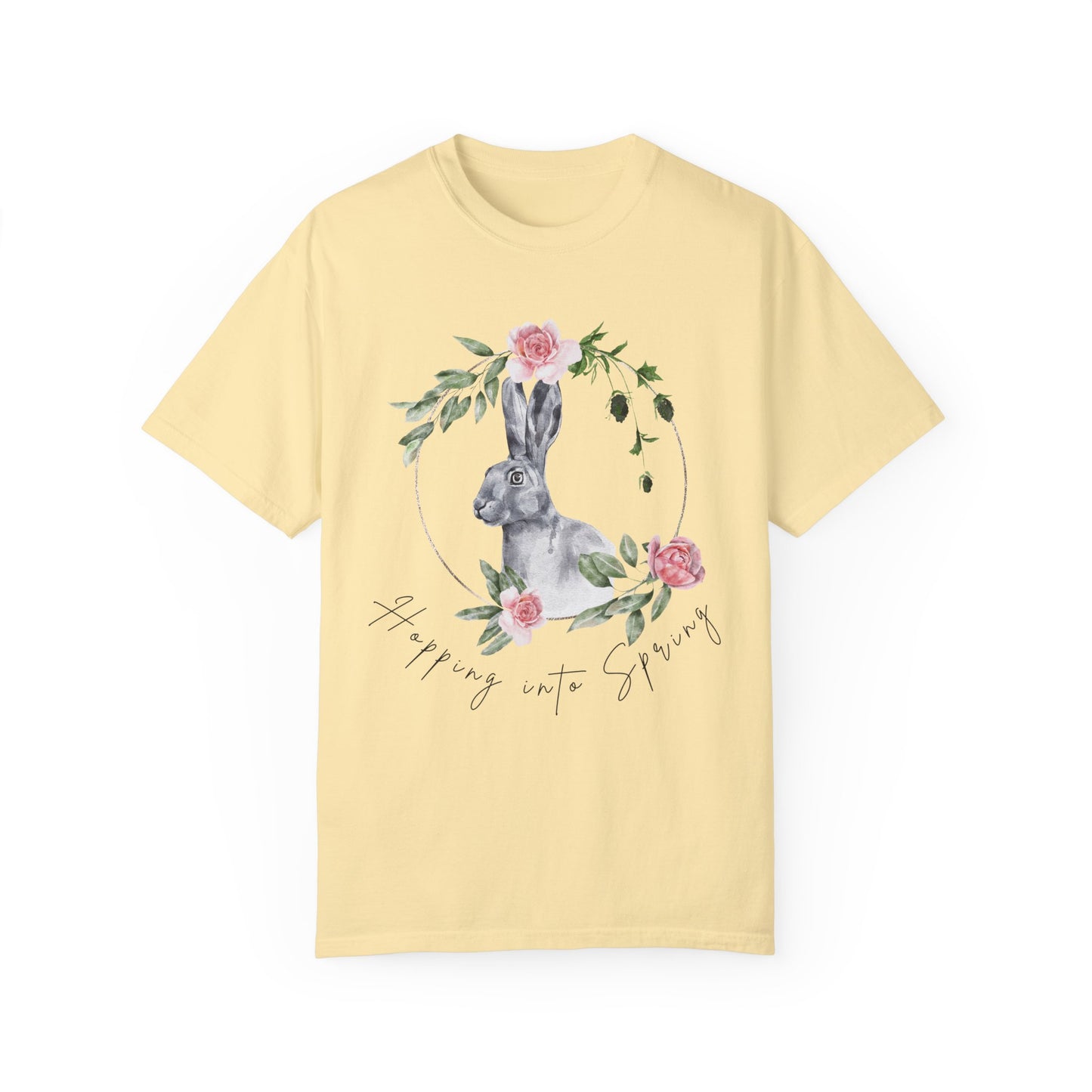 Flat lay of the "Hoppin' into Spring" T-Shirt, highlighting the garment-dyed fabric's texture and the durable double-needle stitching. The watercolor bunny and floral wreath design are clearly visible. Color Banana