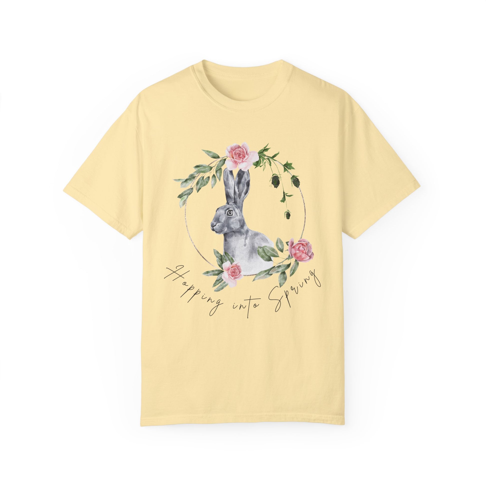 Flat lay of the "Hoppin' into Spring" T-Shirt, highlighting the garment-dyed fabric's texture and the durable double-needle stitching. The watercolor bunny and floral wreath design are clearly visible. Color Banana