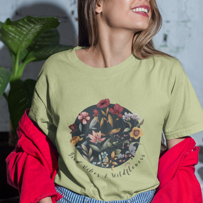 "Hello Spring: Good Vibes & Wildflowers" Unisex Ultra Cotton Tee, featuring a delicate watercolor illustration of various wildflowers, including [mention a few specific flowers like "poppies," "daisies," "lavender," etc.], arranged in a natural and flowing design, with the text "Good Vibes & Wildflowers" incorporated into the artwork, modeled by a woman wearing size M. Color Pistaccio